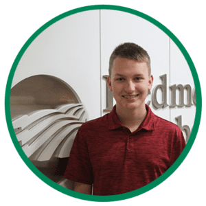 Student who won a scholarship standing in front of the Piedmont Electric logo.