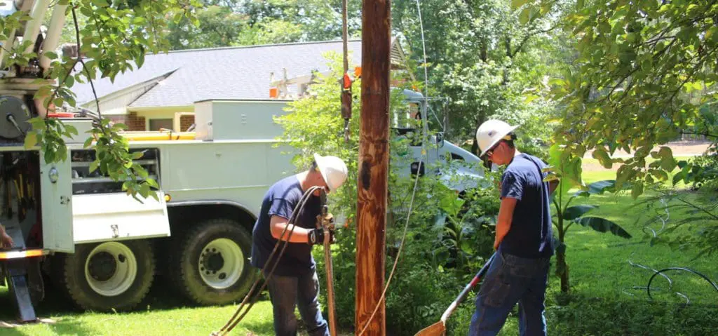 Lineworker intern helping set a power pole.