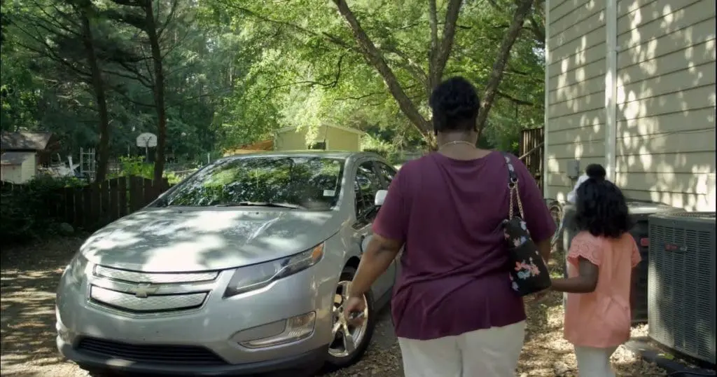 Electric vehicle with parent and child outdoors.