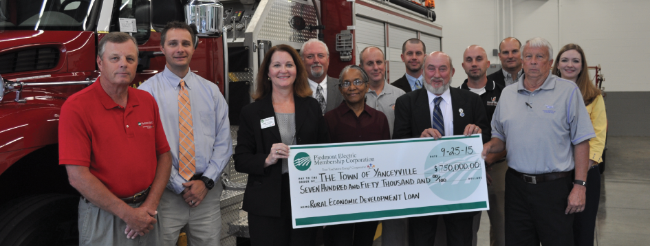 PEMC Employees and Yanceyville officials pose with large donation check in front of fire engine