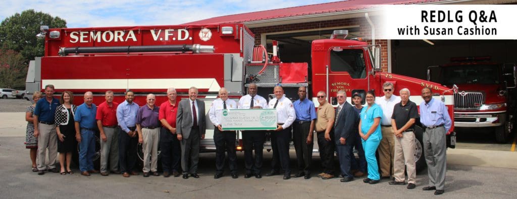 Photo of REDLG ceremony attendees in front of a Semora VFD truck holding a giant check. Text says "REDLG Q&A with Susan Cashion".